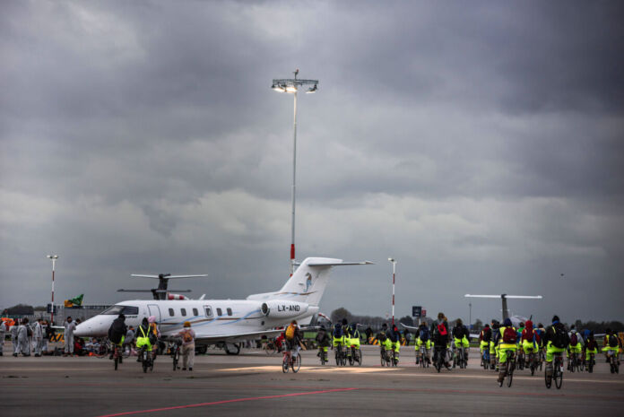 Ein Flugzeug steht startbereit auf dem Flughafen. Um das Flugzeug herum sind die Fluggäste, die an Bord gehen, das Sicherheitspersonal und die Stewards.