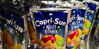 In einem Regal stehen viele Packungen von Capri Sun in den klassischen Sorten Orange und Multi Vitamin. Der Saft ist bei Kindern und Erwachsenen gleichermaßen beliebt.