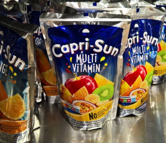 In einem Regal stehen viele Packungen von Capri Sun in den klassischen Sorten Orange und Multi Vitamin. Der Saft ist bei Kindern und Erwachsenen gleichermaßen beliebt.