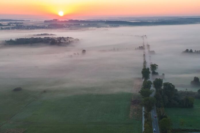 Ein Sonnenuntergang taucht einen wunderschönen See in sanftes Licht. Das Moor ist in Nebel gehüllt und eine einzigartige Attraktion für Touristen.