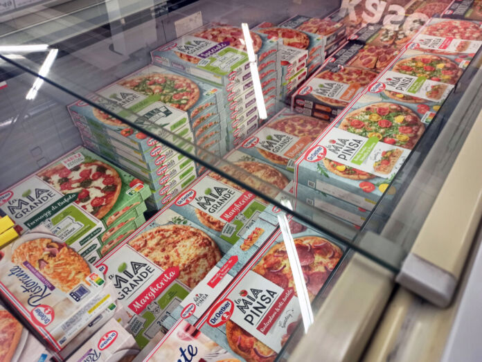 In der Kühltruhe eines Supermarktes liegen verschiedene Sorten von Pizza nebeneinander. Die Pizzakartons sind alle von einer bei Verbrauchern beliebten Marke.