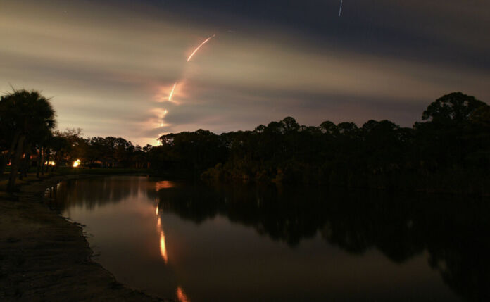 In der Nacht sind Blitze und Lichterscheinungen am Himmel zu sehen. Dieses ungewöhnliche Naturschauspiel zeichnet sich am Himmel und im Wald ab. Im Vordergrund fließt ein Fluss.