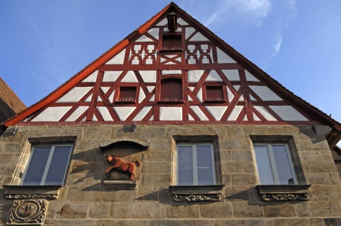 Die Fassade eines alten Fachwerkhauses einer alten Metzgerei. Es befinden sich viele klassische und historische Ornamente sowie die Giebel als Erkennungszeichen auf der Hausfront. Auf der Hauswand ist die Figur eines Stiers angebracht.