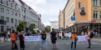 Klimaaktivisten oder Teilnehmer der Klimaaktion blockieren die Straße mit ihren Bannern. Sie tragen orangene Westen und lassen die Autos nicht mehr durch. Es können sich dabei Mitglieder der letzten Generation befinden.