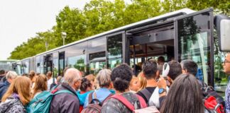 Dicht gedrängt stehen die Menschen vor dem Eingang eines Busses. Es kann sich um einen Schulbus handeln oder um einen Bus des Schienenersatzverkehrs, der alle Fahrgäste aufnimmt und an ihr Ziel bringt.