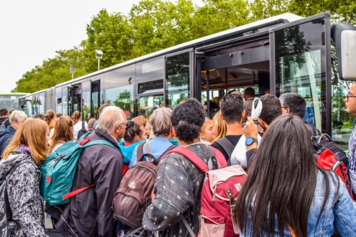 Dicht gedrängt stehen die Menschen vor dem Eingang eines Busses. Es kann sich um einen Schulbus handeln oder um einen Bus des Schienenersatzverkehrs, der alle Fahrgäste aufnimmt und an ihr Ziel bringt.