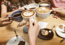 Mehrere Frauen treffen sich auf einen Kaffee oder Cappuccino. Dazu gibt es Gebäck, einen Kuchen oder ein Stück Torte. Sie befinden sich in einem Café.