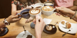 Mehrere Frauen treffen sich auf einen Kaffee oder Cappuccino. Dazu gibt es Gebäck, einen Kuchen oder ein Stück Torte. Sie befinden sich in einem Café.