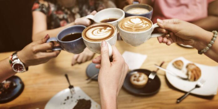 Mehrere Frauen treffen sich auf einen Kaffee oder Cappuccino. Dazu gibt es Gebäck, einen Kuchen oder ein Stück Torte. Sie befinden sich in einem Café.