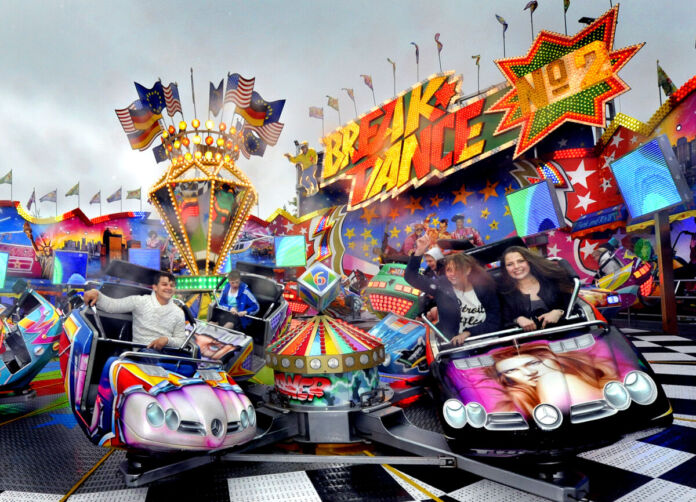 Ein großes Fahrgeschäft auf einem Jahrmarkt lädt zum Mitfahren ein. Es ist kein Kinderkarussell, sondern ein Spezialgeschäft für Jugendliche mit hoher Geschwindigkeit.