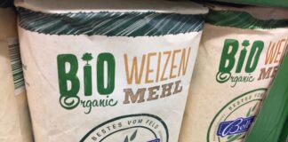 Im Regal eines Discounters oder Supermarktes stehen mehrere Packungen Weizenmehl. Die Beschriftung zeigt, dass es sich um ein Bio-Produkt und um die Eigenmarke eines Discounters oder Supermarktes handelt.