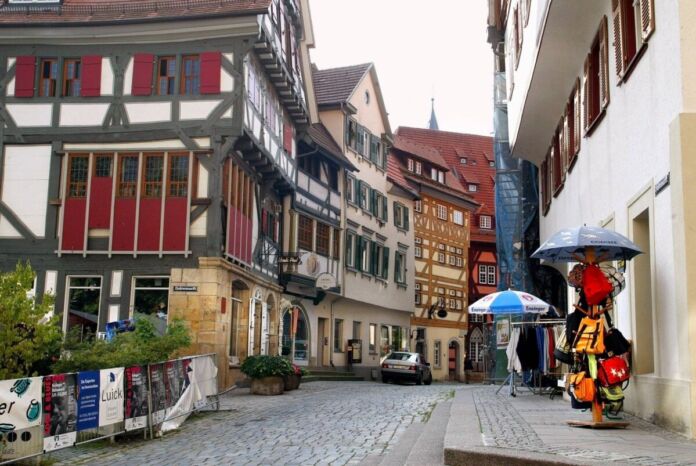 In einer Straße stehen alte Fachwerkhäuser. Die Häuser sind sehr alt und eine beliebte Attraktion bei Touristen. Die Straße ist bei Besuchern aufgrund ihres Charmes sehr beliebt.