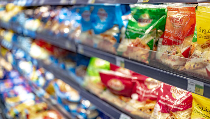 Verschiedene Sorten geriebener Käse im Supermarkt. Es gibt eine vielfältige Auswahl an Käse und Marken in Plastikbeuteln, die ordentlich sortiert nebeneinander stehen und in farbenfrohen Verpackungen angeboten werden.