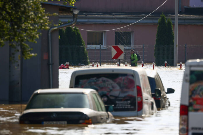 Eine Straße mit Autos ist komplett überflutet. Die Fahrzeuge stehen bis zu den Scheinwerfern im Hochwasser. Für E-Autos könnte das besonders gefährlich sein.