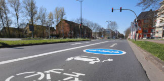 Das Bild einer leeren Straße, dahinter eine rote Ampel. Im Vordergrund sieht man Extra-Fahrspur. Diese kann von Fahrradfahrern, Bussen, aber auch E-Autos genutzt werden.