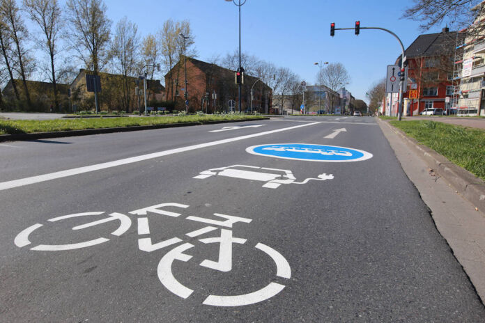 Das Bild einer leeren Straße, dahinter eine rote Ampel. Im Vordergrund sieht man Extra-Fahrspur. Diese kann von Fahrradfahrern, Bussen, aber auch E-Autos genutzt werden.